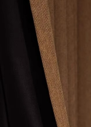 a close-up view of a black curtain with a brown fabric panel, creating a contrast between the two materials.
