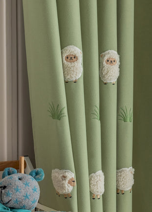 a teddy bear sitting next to a curtain with sheep on it