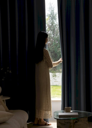 a woman standing in front of a window in a living room