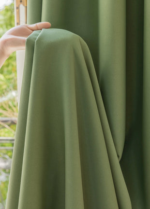 a person holding a green curtain in front of a window