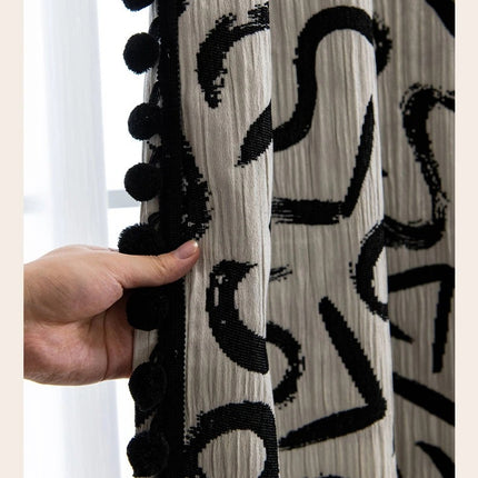 a hand holding a curtain with black and white designs