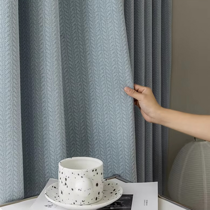 a person is holding a coffee cup in front of a curtain