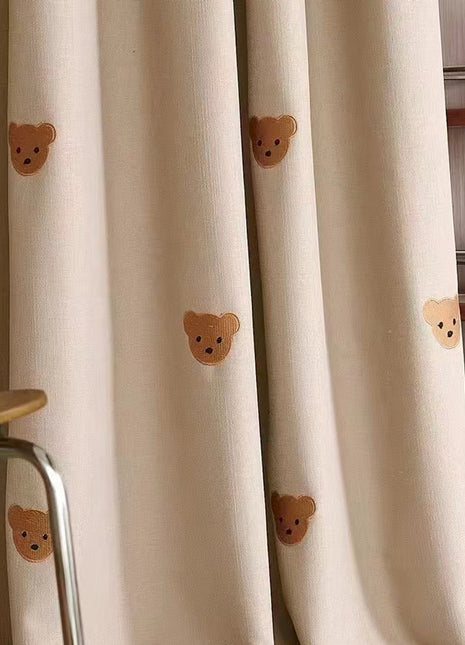 a room with a chair and a curtain with teddy bears on it