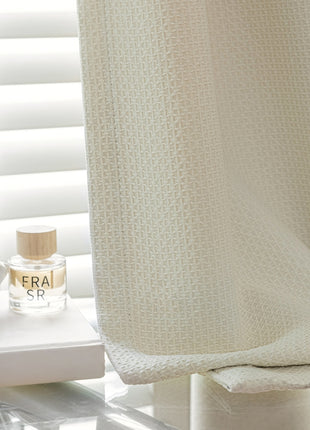 a white shower curtain with a bottle of perfume next to it