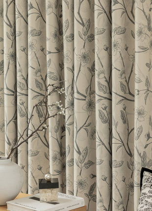 a vase with a branch on a table next to a window