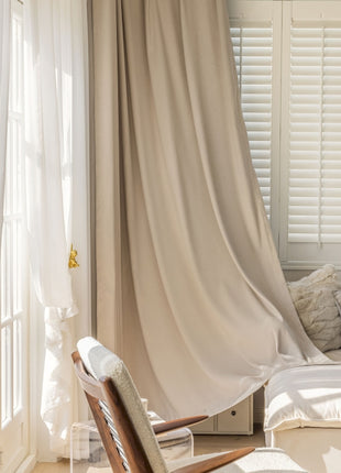 a chair sitting in front of a window covered in curtains