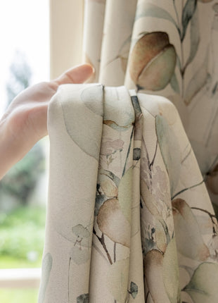 a hand is holding a curtain with a flower pattern