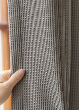 a person holding onto a curtain in front of a window