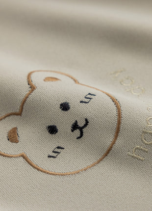 a close up of a teddy bear on a white shirt