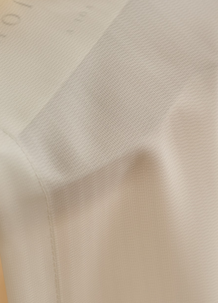 a close-up view of a white fabric, possibly a curtain or a piece of clothing, with a blurred background.
