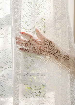 a woman's hand is seen through a lace curtain