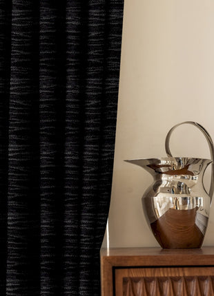 a silver vase sitting on top of a wooden table