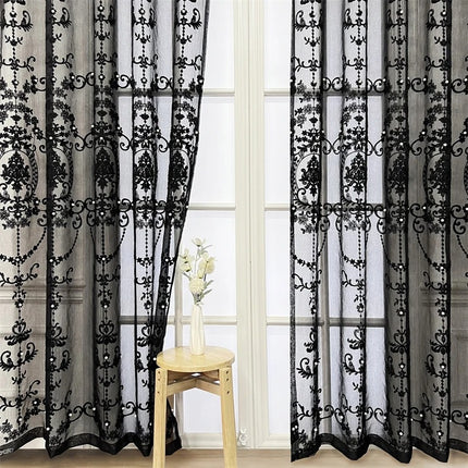 a window with sheer curtains and a vase of flowers