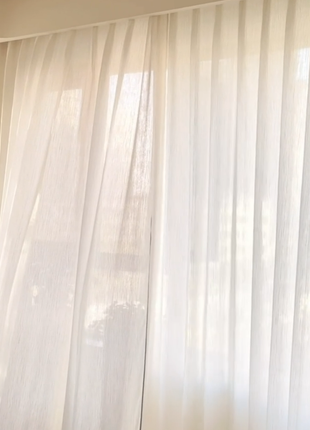 a window with white curtains, partially open, allowing sunlight to stream through.