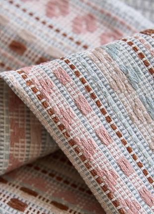 a close-up view of a textured fabric with a repeating pattern of pink and white squares.