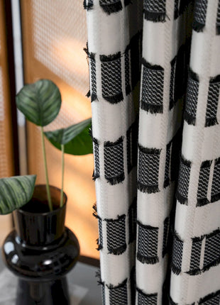 a black vase with a green plant in it