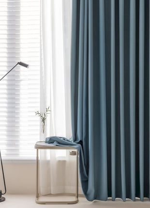 a living room with a lamp and a blue curtain