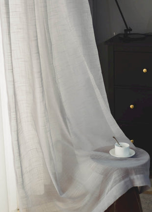a table with a cup on it in front of a curtain