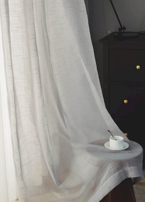 a table with a cup on it in front of a curtain