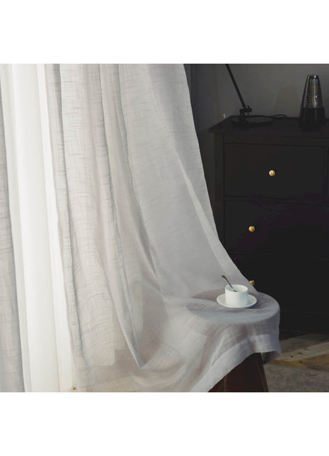 a table with a cup on it in front of a curtain