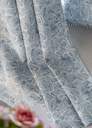 a close up of a curtain with a vase of flowers in front of it