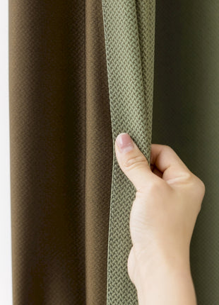 a hand is holding a curtain in front of a window