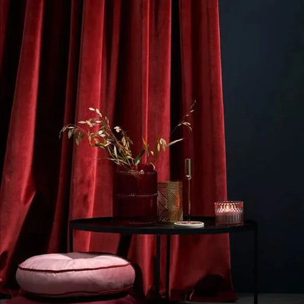 a black table with a pink cushion and a red curtain