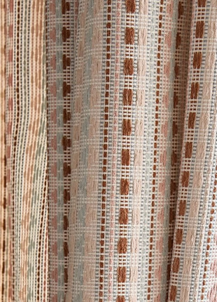 a close-up view of a curtain with a repeating pattern of brown and white stripes.