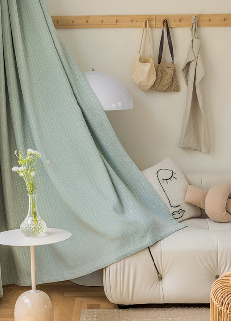 a living room with a white couch and a green curtain