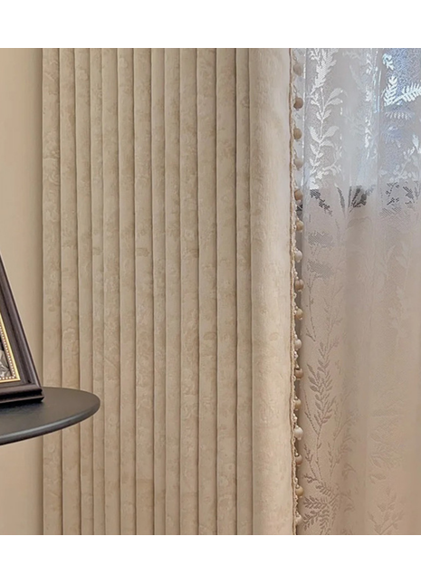 a beige curtain with vertical lines, a framed picture on a shelf, and a window with white lace curtains.