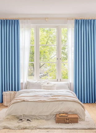 a bedroom with blue curtains and a white bed