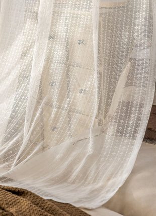 a bed with a white sheer curtain hanging over it