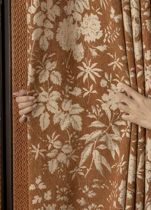 a woman's hand on a curtain with a floral pattern
