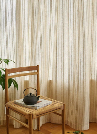 a tea pot on a chair in front of a curtain