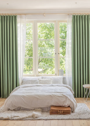 a bedroom with a large bed and green curtains