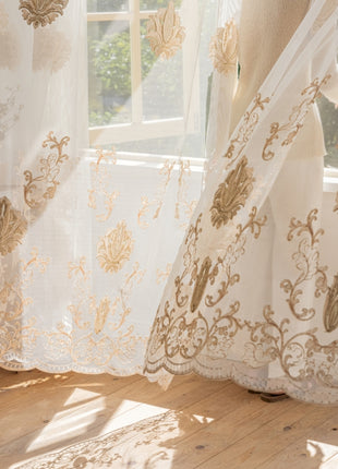 a white curtain with a gold design hanging in front of a window