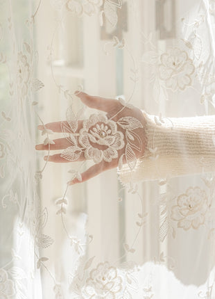 a woman's hand is seen through a sheer curtain