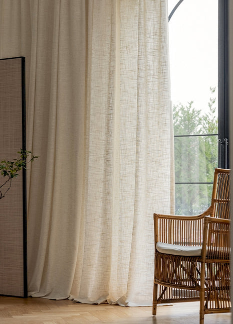 a chair sitting next to a window with a white curtain
