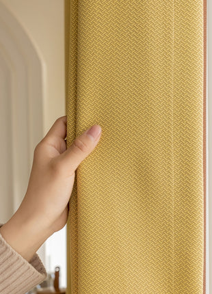 a person is holding a yellow curtain in their hand