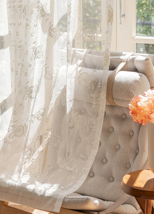 a chair with a vase of flowers on it next to a window