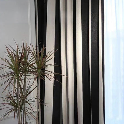 a black and white striped curtain next to a potted plant