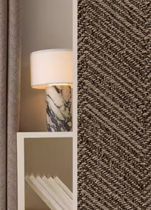a lamp with a white shade and a marble base, placed on a white shelf. The shelf has a few books on it. The background has a textured fabric with a zigzag pattern.