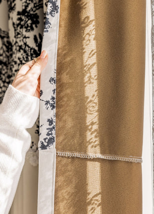 a person holding a curtain in front of a window