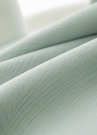 a close up of a bed with a green comforter