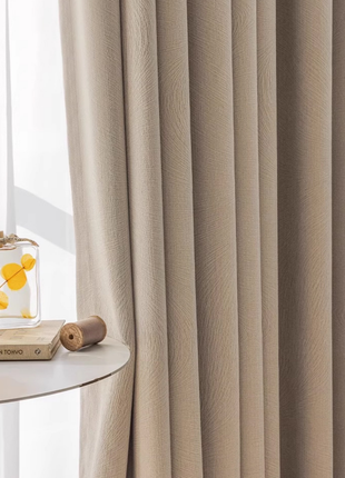 a beige curtain with a white table and a small wooden object, such as a book or a pen, placed on the table.