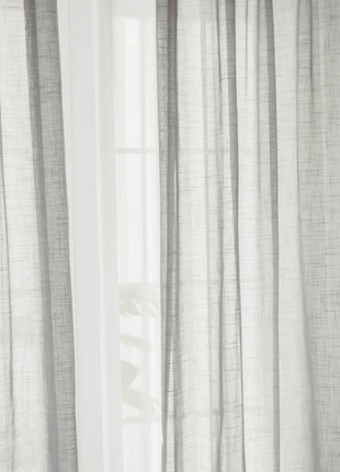 a cat sitting on a window sill in front of a curtain