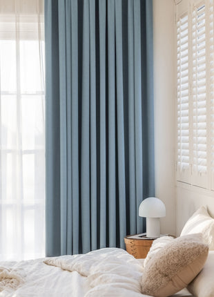 a bedroom with a white bed and blue curtains