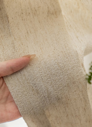a person holding a piece of fabric with a plant in the background