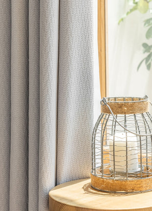 a white candle sitting on top of a table next to a window