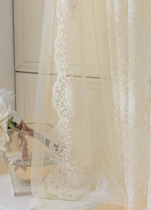 a vase with flowers on a table next to a curtain
